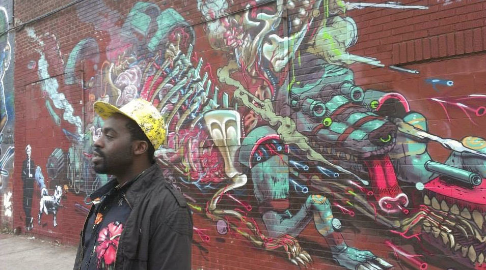 Tripoli in a yellow hat in front of a colorful mural